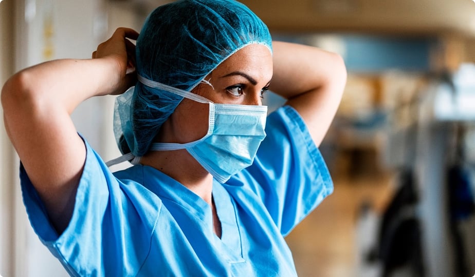 nurse in scrubs putting on a face mask