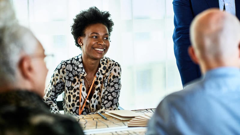 MULHER-EM-MESA-DE-CONFERÊNCIA-SORRINDO-PENSANDO-QUADRO