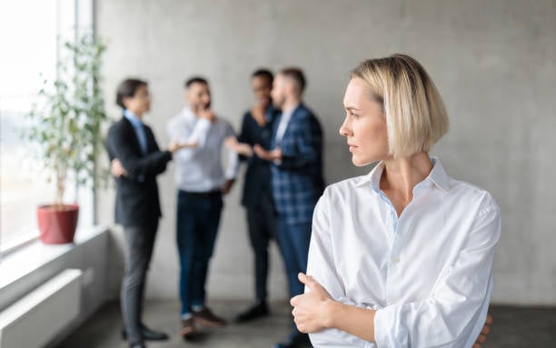 person-looks-over-their-shoulder-employees-chatting-workplace-gossip