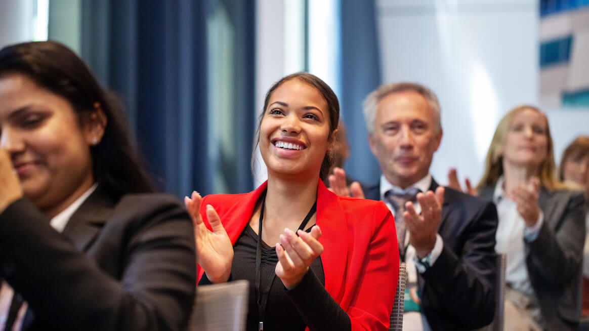 sales-kickoff-team-clapping-person-smiling-at-a-presentation