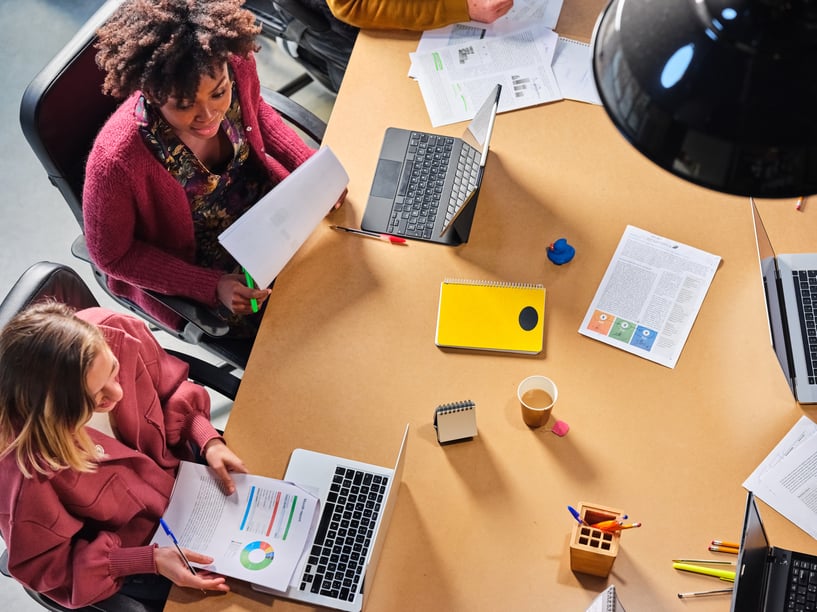 two-employees-talking-at-a-table-office-wellness