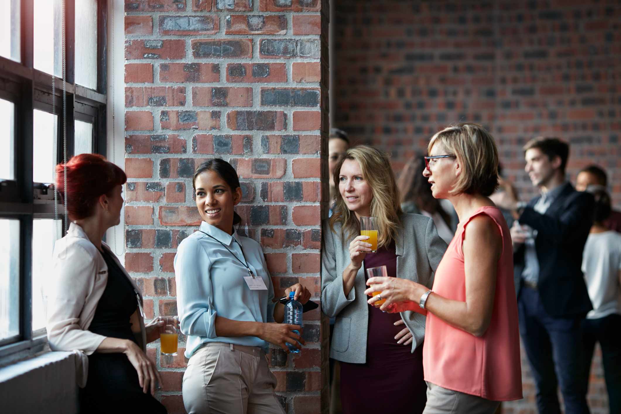 Businesspeople-socializing-by-window-of-auditorium-mom-going-back-to-work-after-10-years