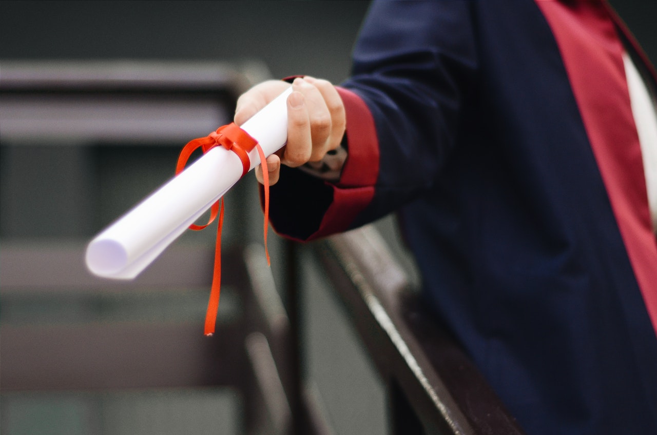 Close-up-of-hand-holding-college-diploma-magna-cum-laude-vs-summa-cum-laude