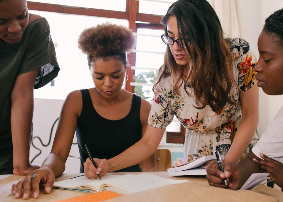 Four-coworkers-reviewing-big-paper-and-writing-on-it-at-meeting-jobs-that-wont-be-automated