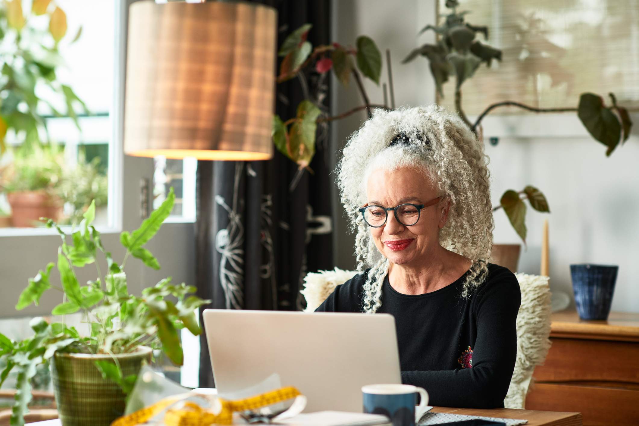 Grey-haired-woman-at-home-smiling-in-front-of-laptop-how-to-make-a-portfolio