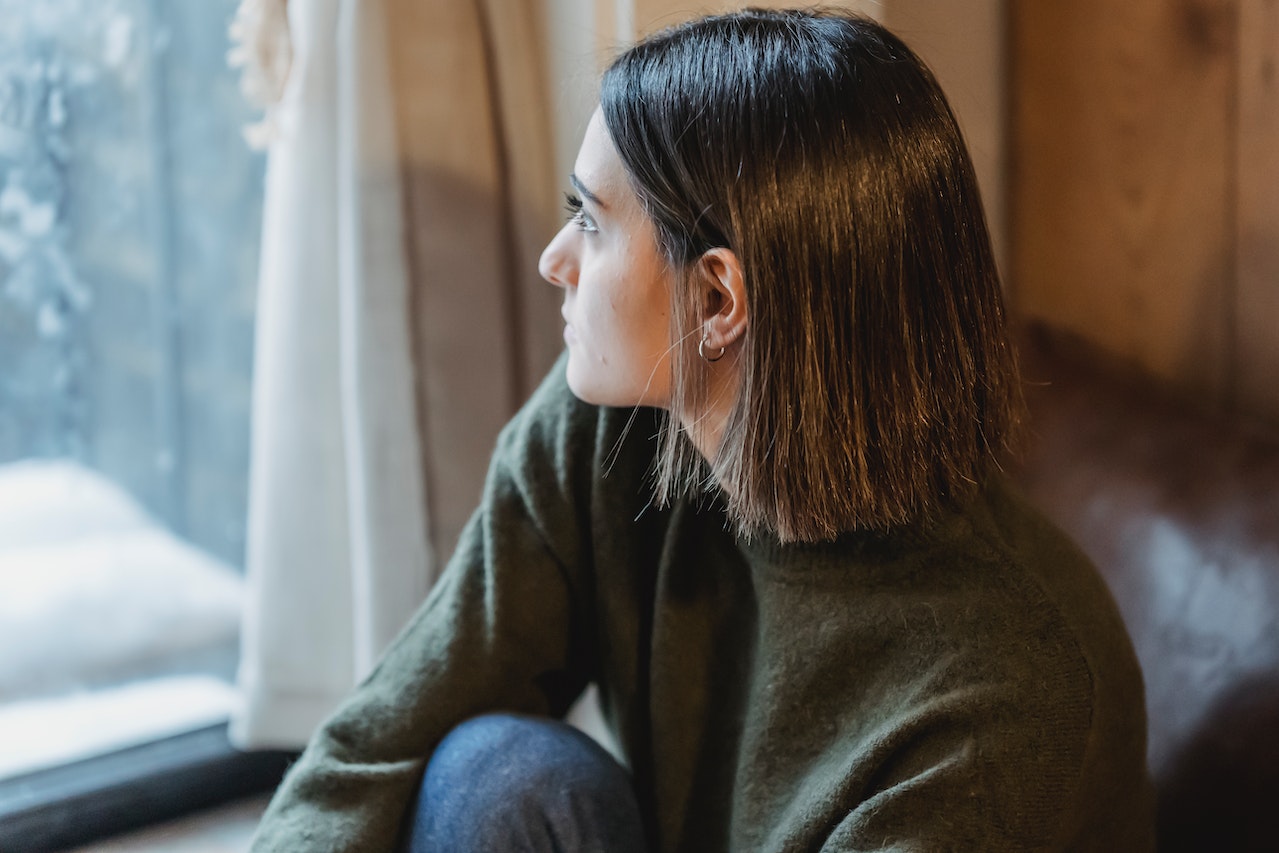 Lonely-woman-looking-out-her-bedroom-window-how-to-handle-homesickness