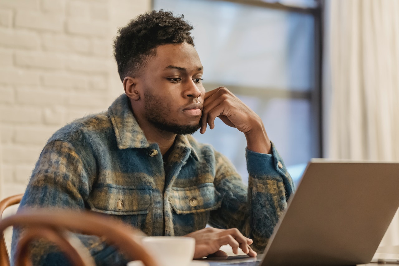 Serious-black-man-working-on-laptop-in-workspace-project-scope