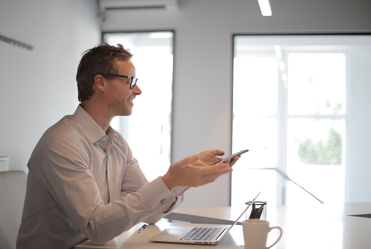 Smiling-adult-businessman-at-table-with-gadgets-holding-presentation-project-scope