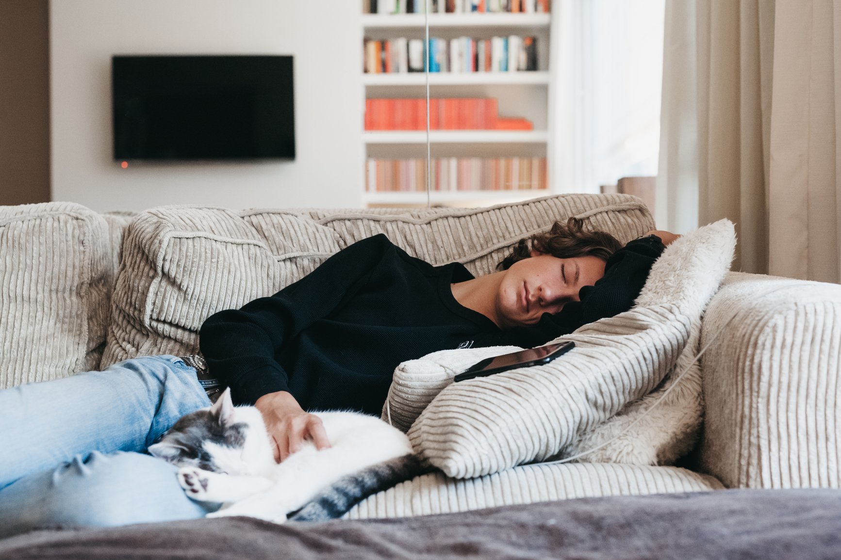 Tired-woman-taking-a-nap-on-the-couch-at-home-with-his-hand-on-his-cat-working-too-much