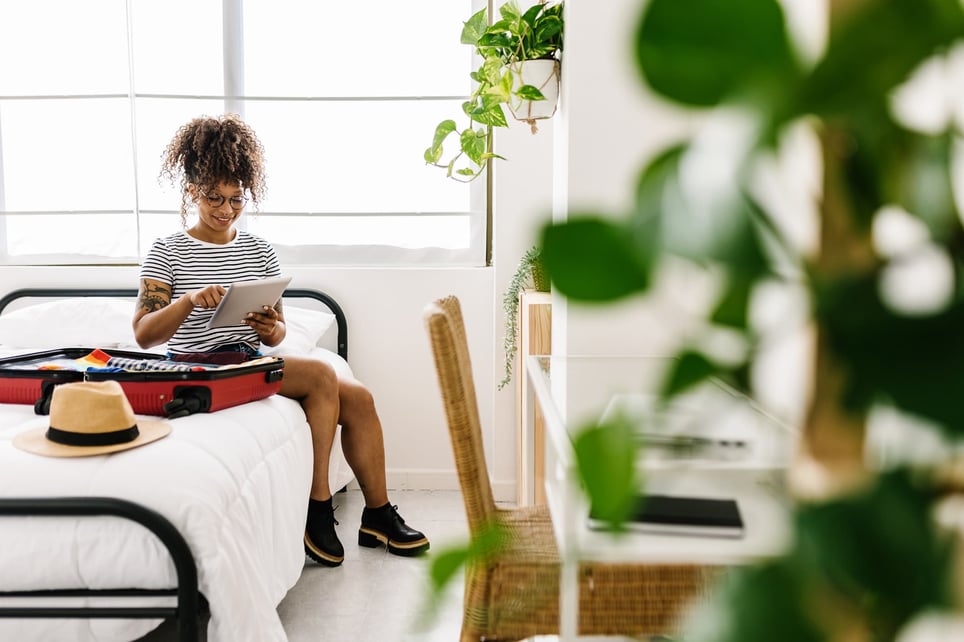 afro-woman-sitting-on-bed-packing-suitcase-full-time-vs-part-time-benefits (1)