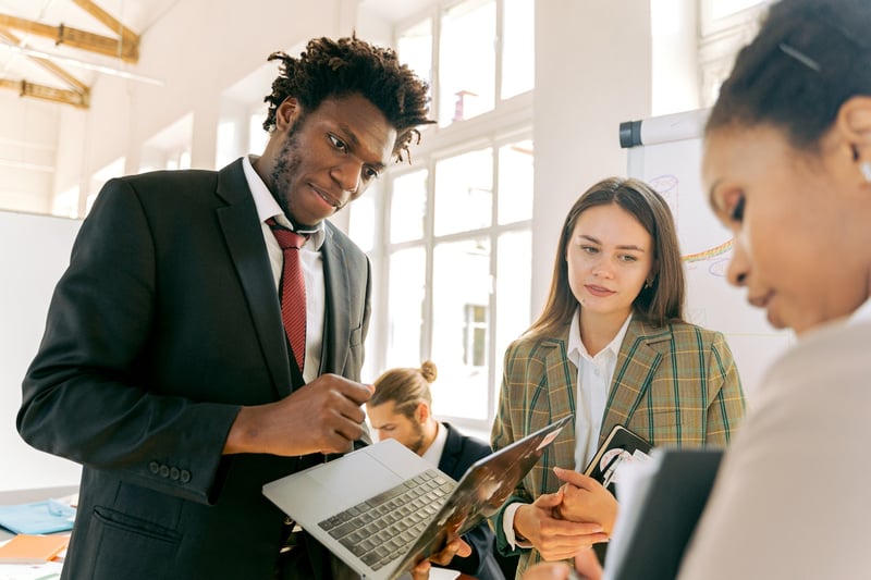 co-workers-discussing-matters-with-computer-in-hand-benefits-of-collaboration