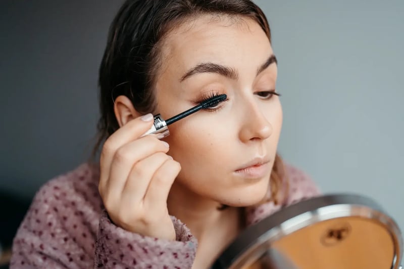 female applying mascara during morning routine