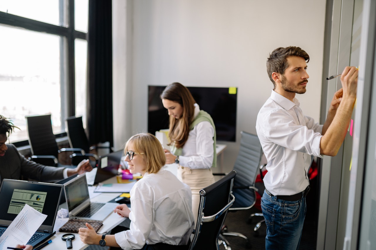 group-of-people-having-meeting-in-office-while-managers-writes-on-whiteboard-project-scope