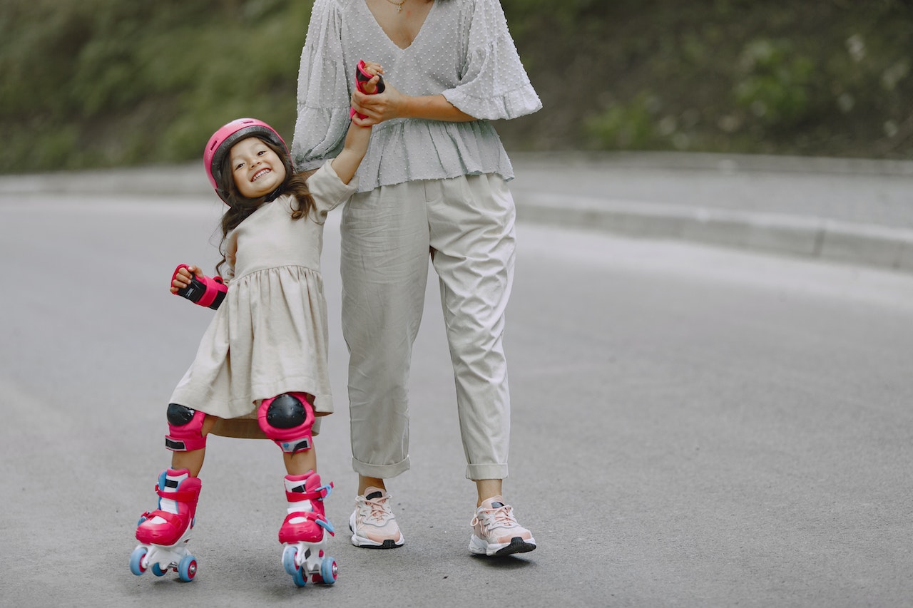 little-girl-with-helmet-on-skating-and-holding-her-mothers-hand-parenting-skills