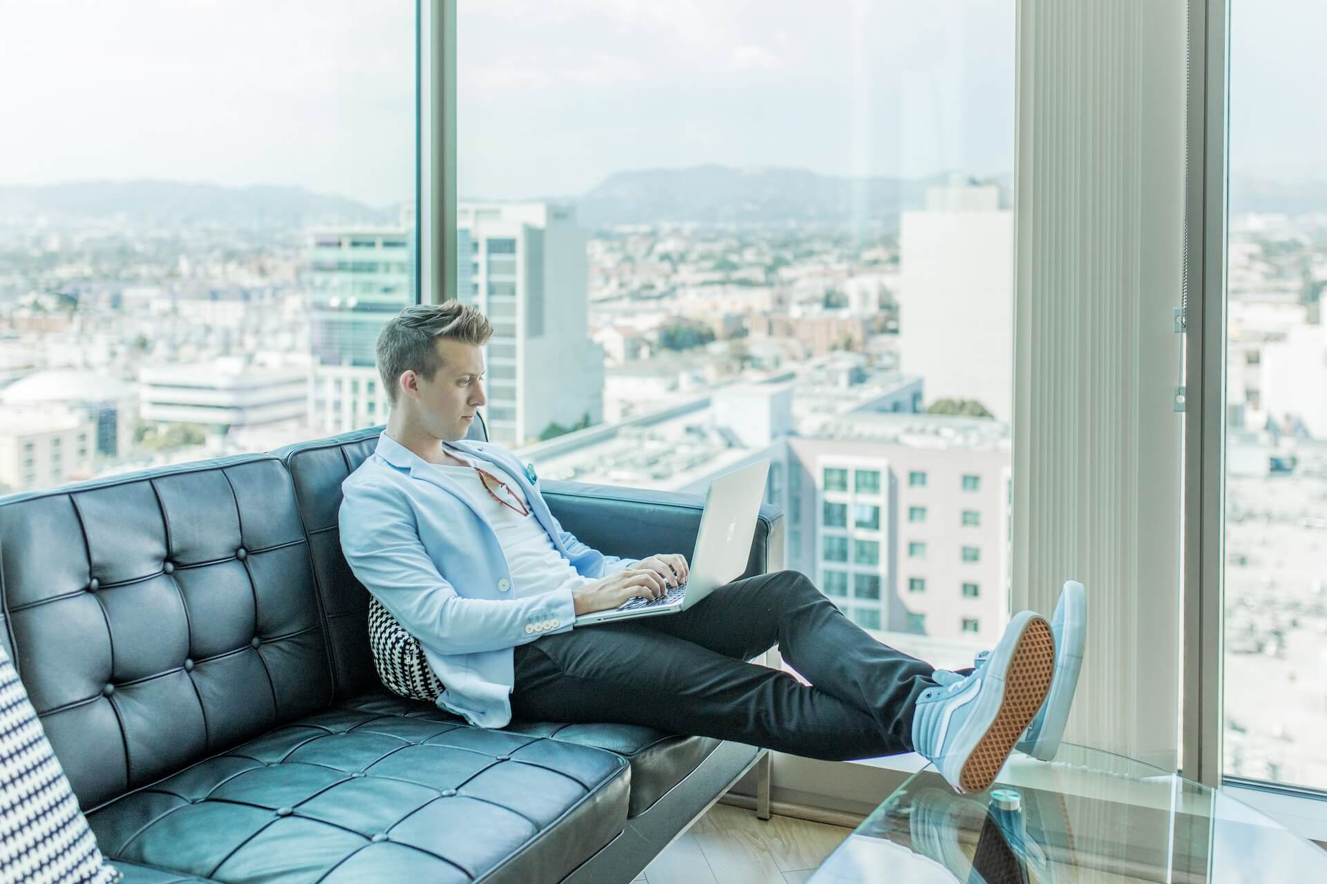 man typing his career plan on black sofe by big window (1)