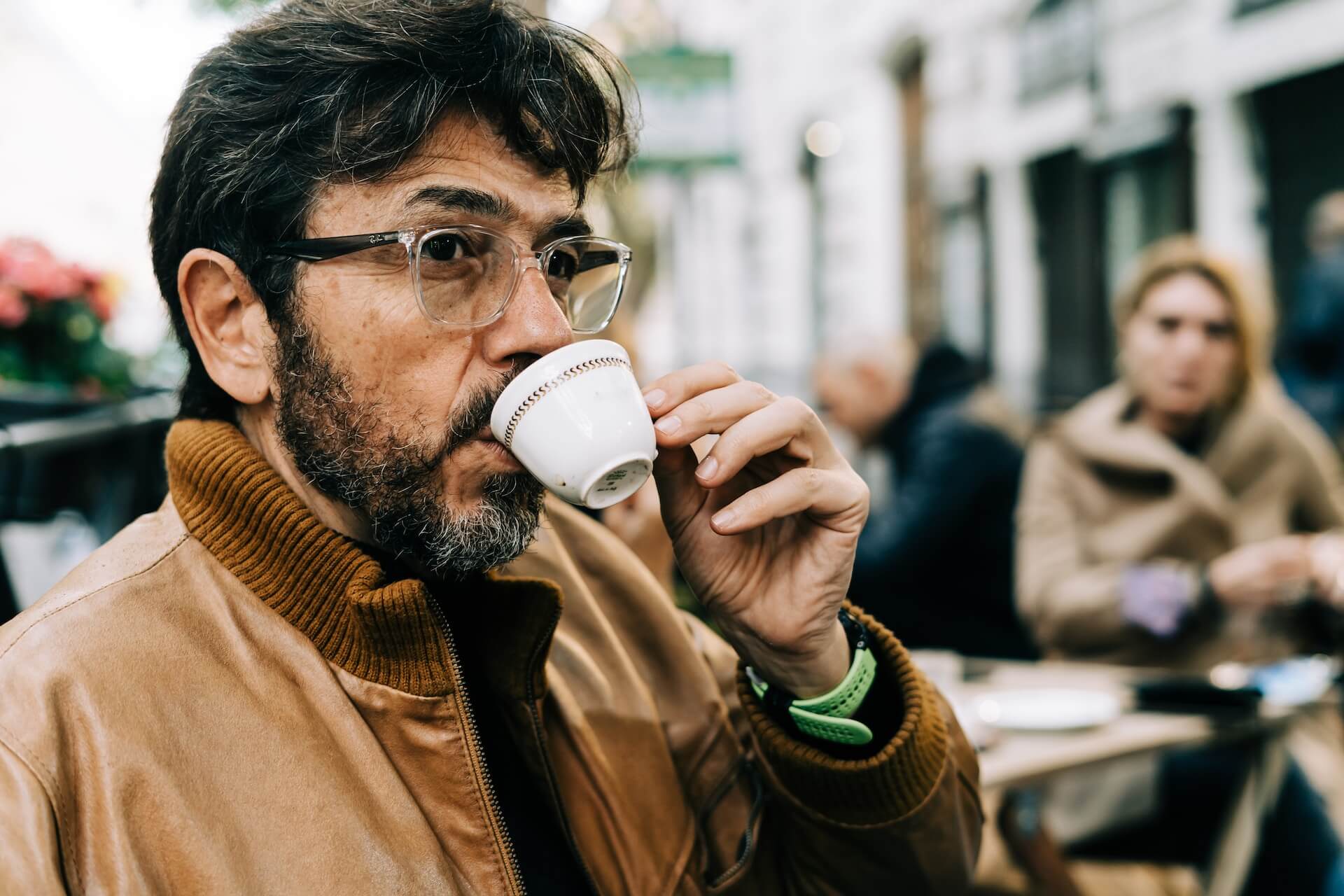 man with beard drinking espresso outside a cafe