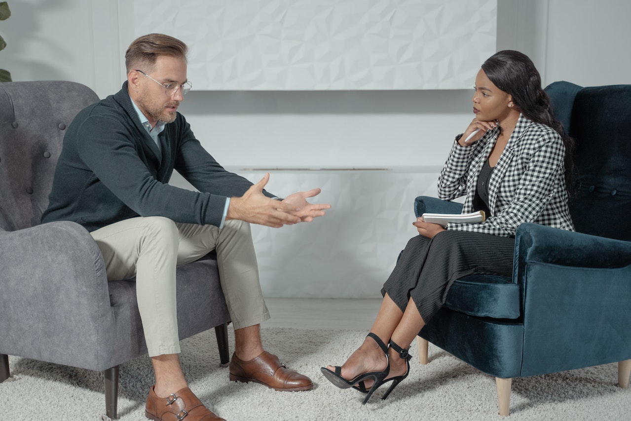 man explaining his case to woman in chair