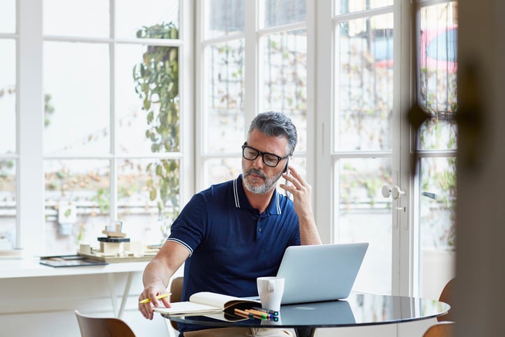 man-using-mobile-phone-while-writing-notes-letter-of-interest