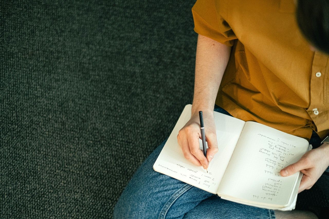 man-writing-on-notebook-sitting-on-the-floor-chat-gpt-cover-letter