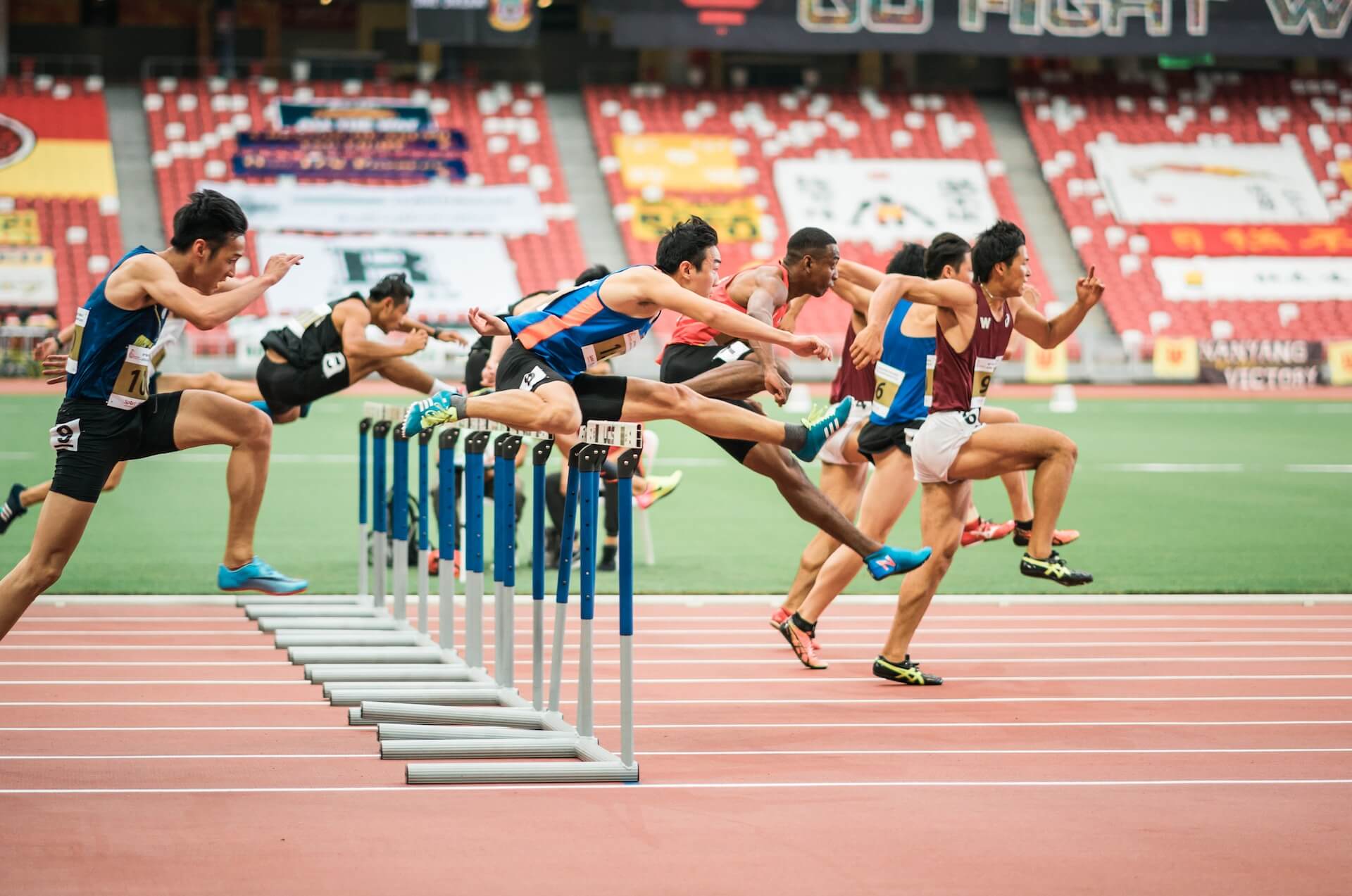 men running jumping over hurdles