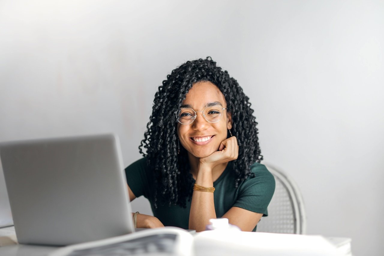 woman-with-hand-on-her-chin-smiling-in-front-of-notebook-positivity