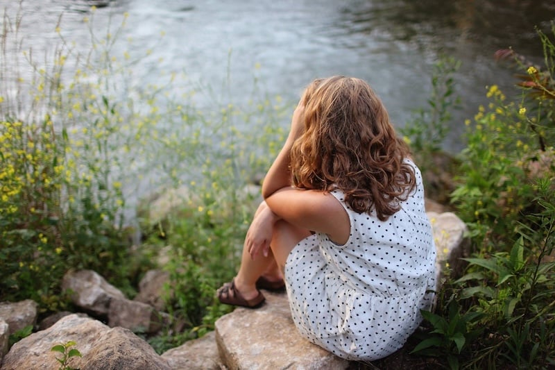 women-sitting-by-the-river-with-hand-on-her-head-insecurity