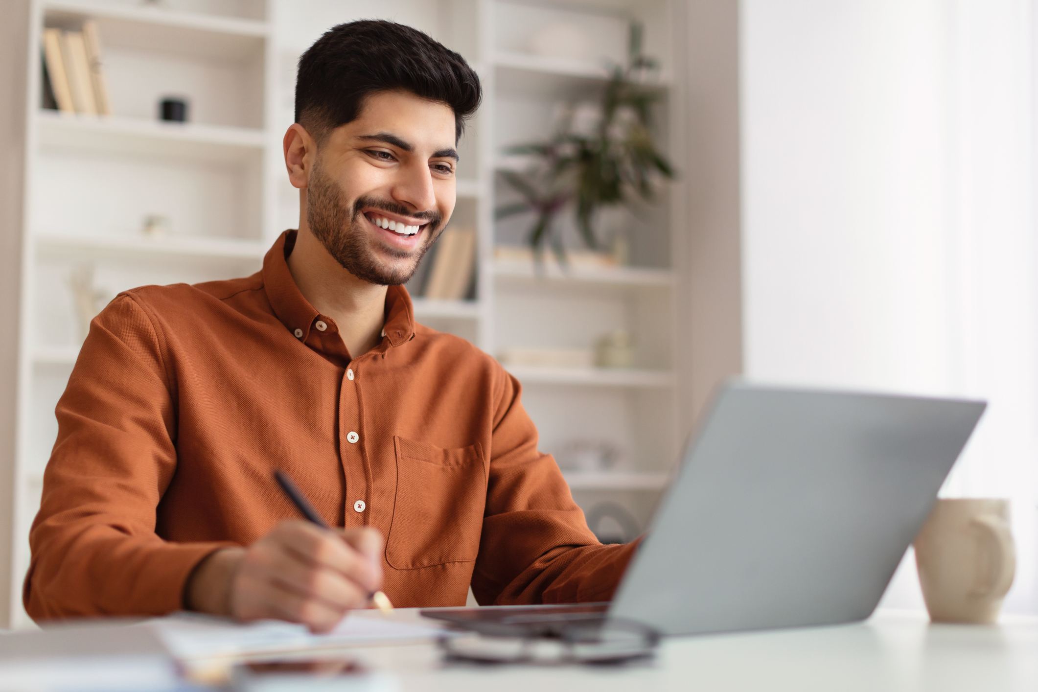 smiling-Arab-man-using-laptop-and-writing-reentering-the-workforce