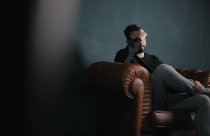 triggered man sitting in dark blue room