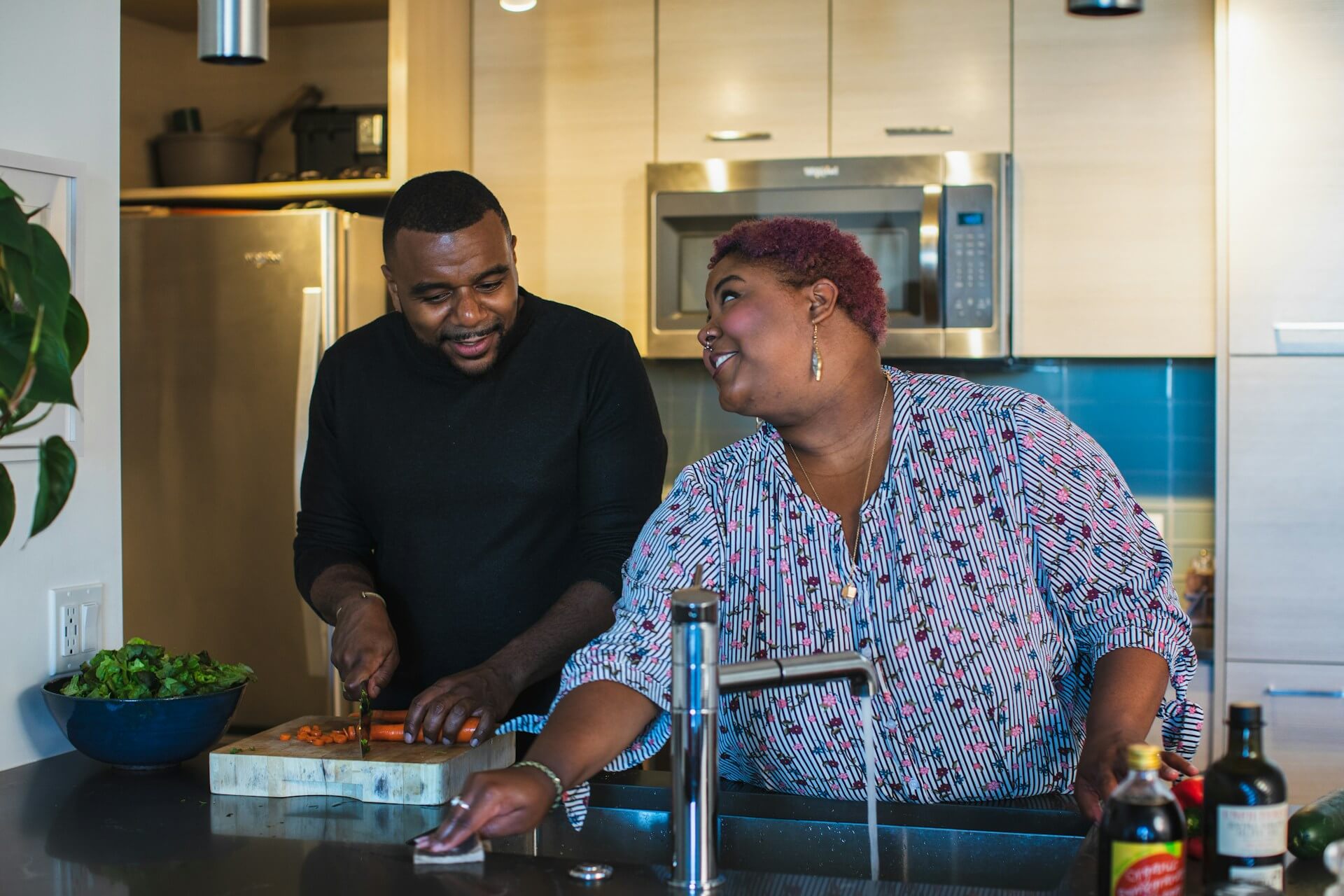 two people of color cooking smiling together in kitchen