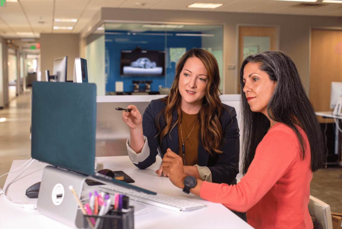 two women looking at computer screen reading about career pathing