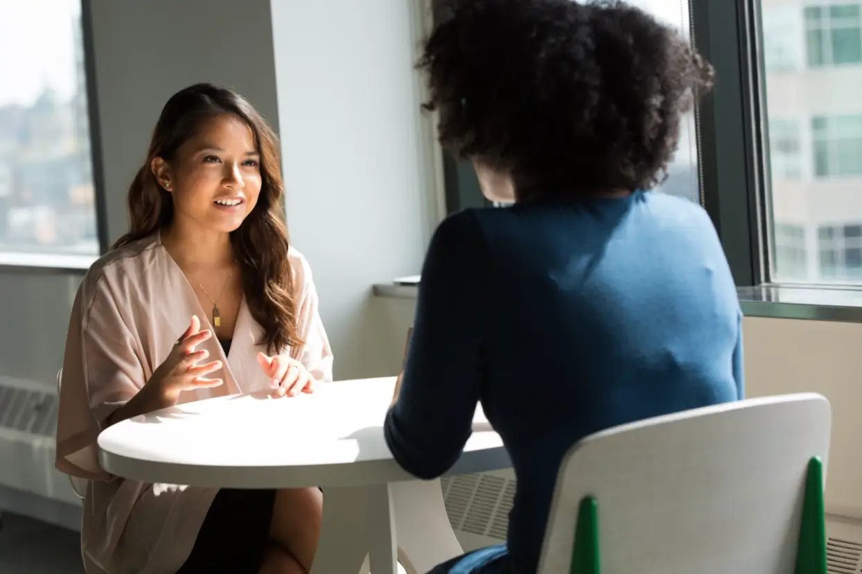 two women sitting at table discussing their career paths