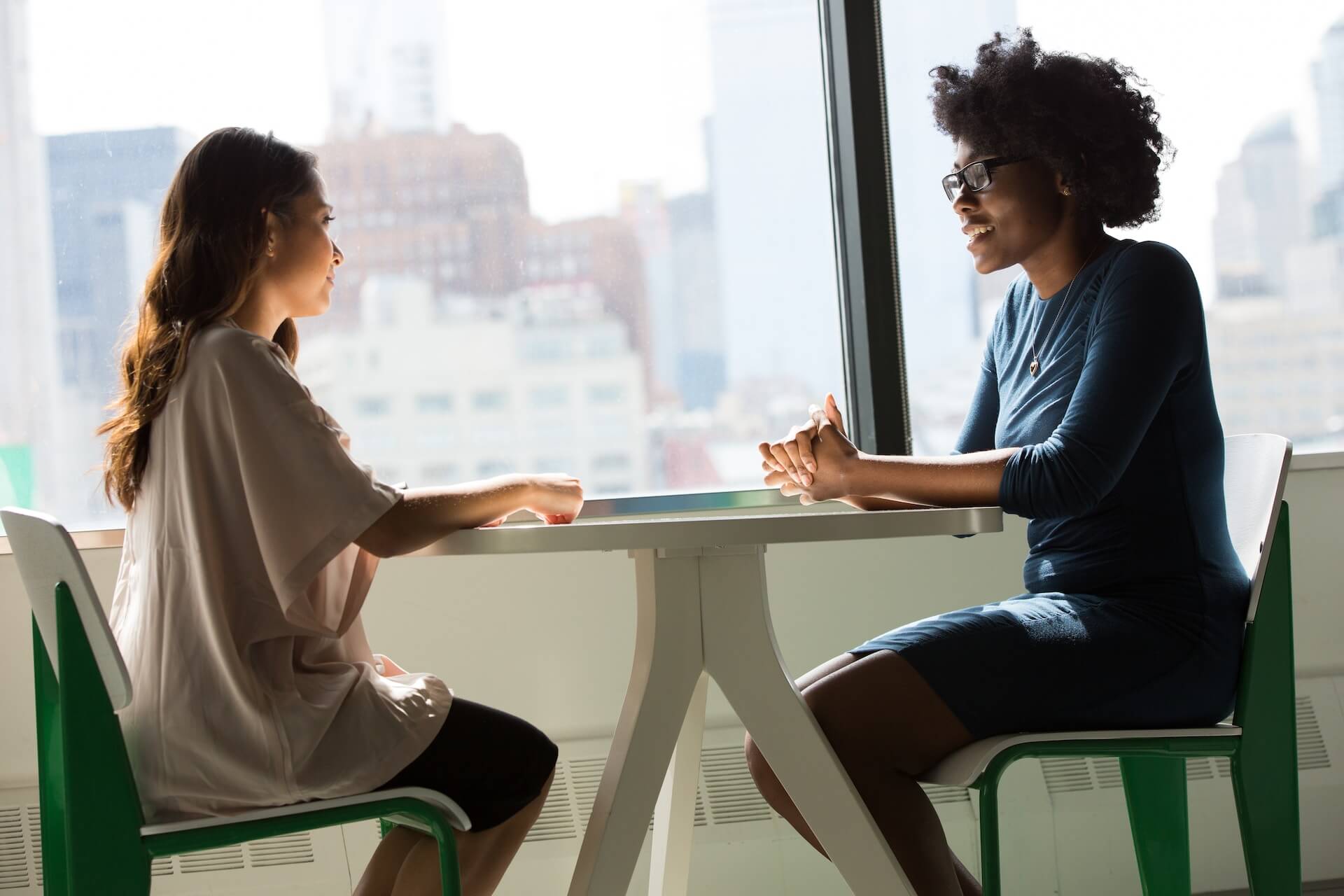 two women sitting at table in window talking