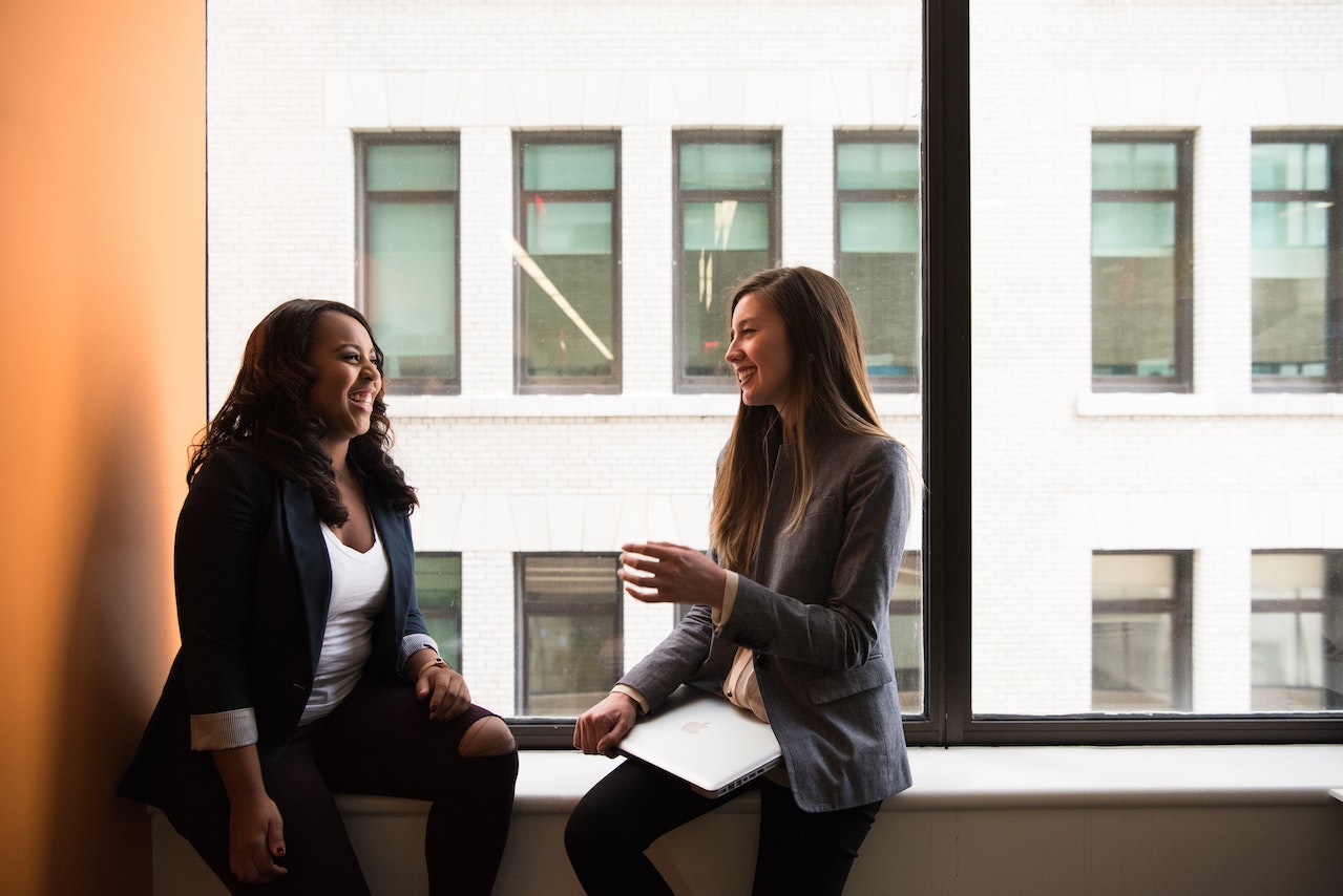 two woman sitting laughing in office