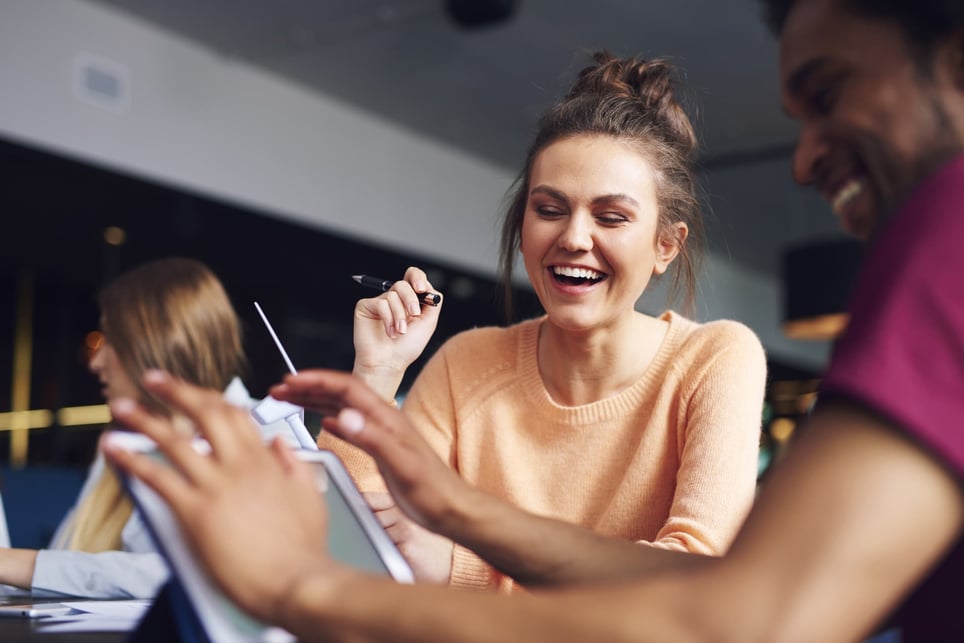 two-young-workers-laughing-and-looking-at-a-tablet-ice-breakers-for-virtual-meetings