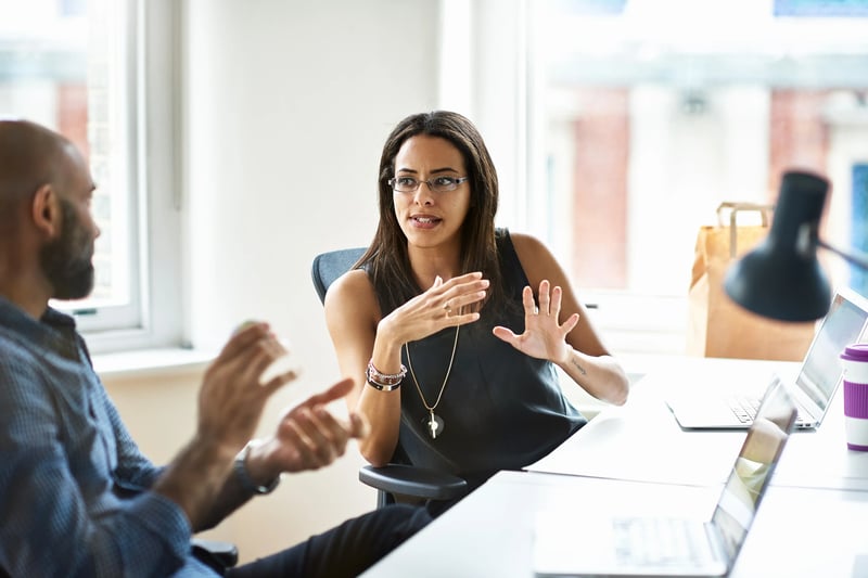 woman communicating with male coworker at desk (1)