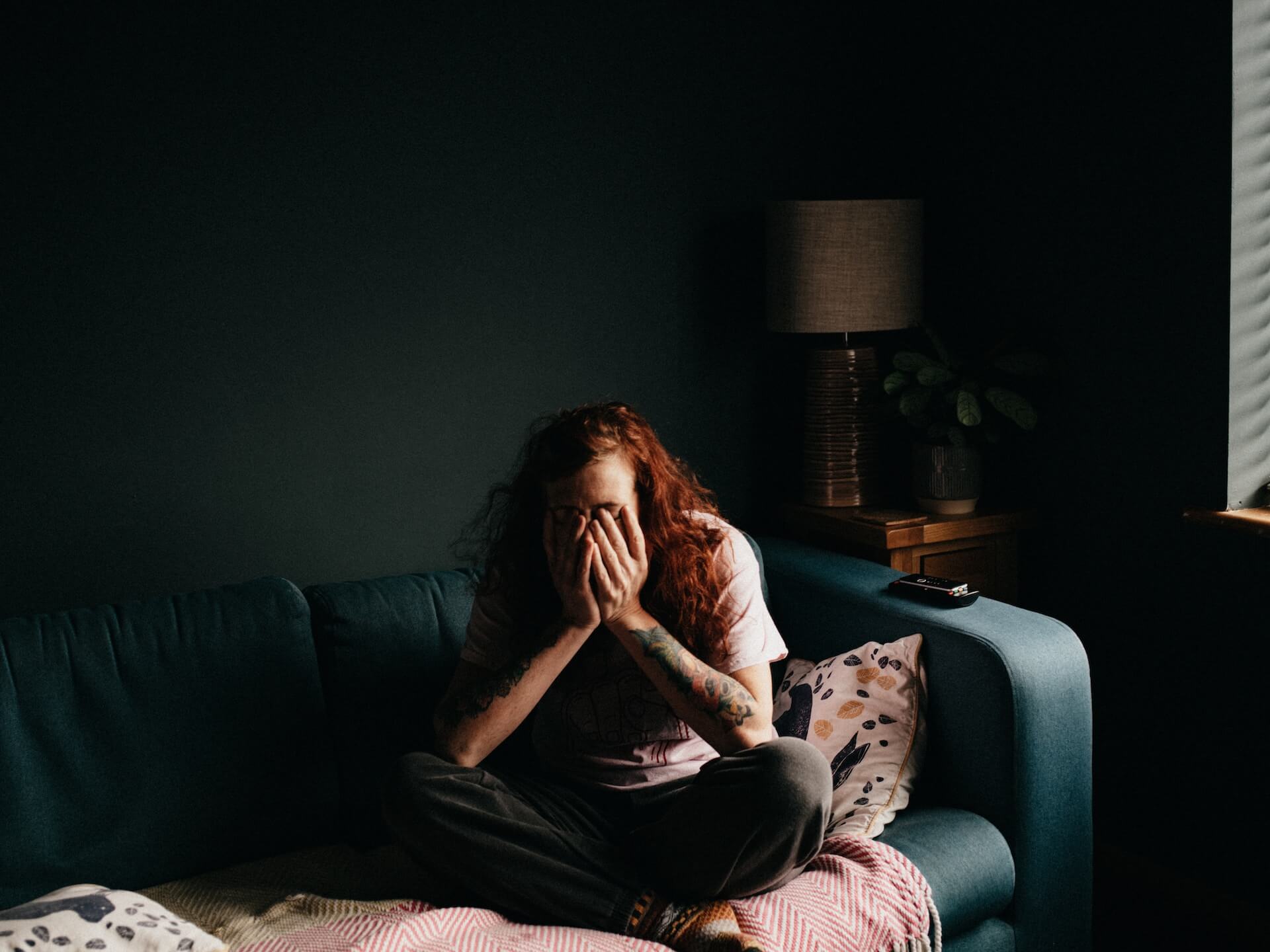 woman in dim room with hands over her face tired