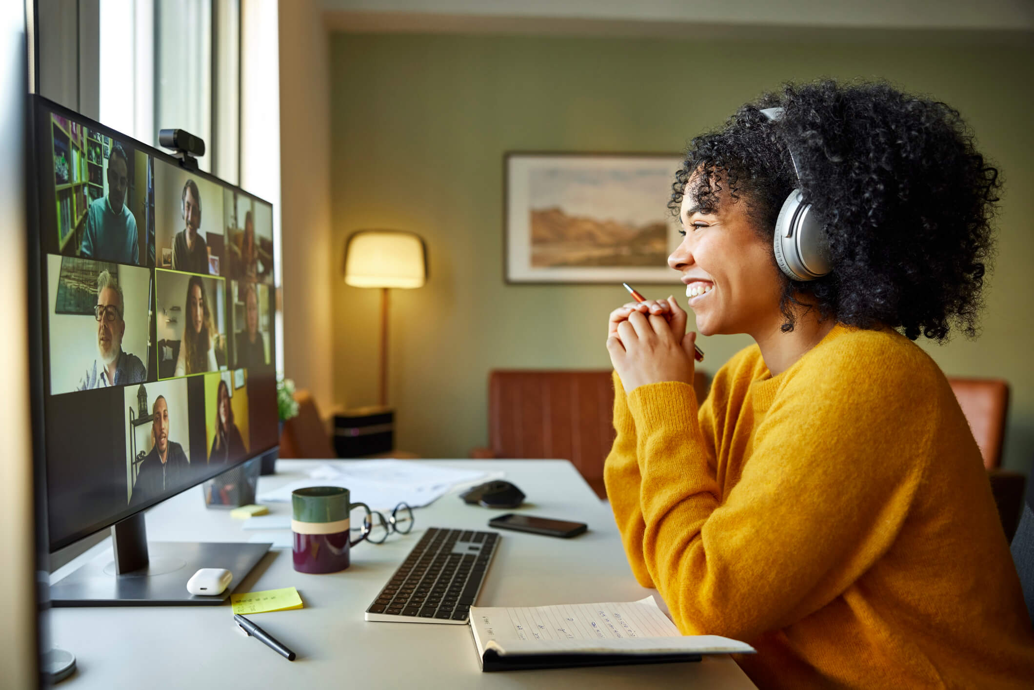 woman in yellow and headphones smiling on virtual call (1)