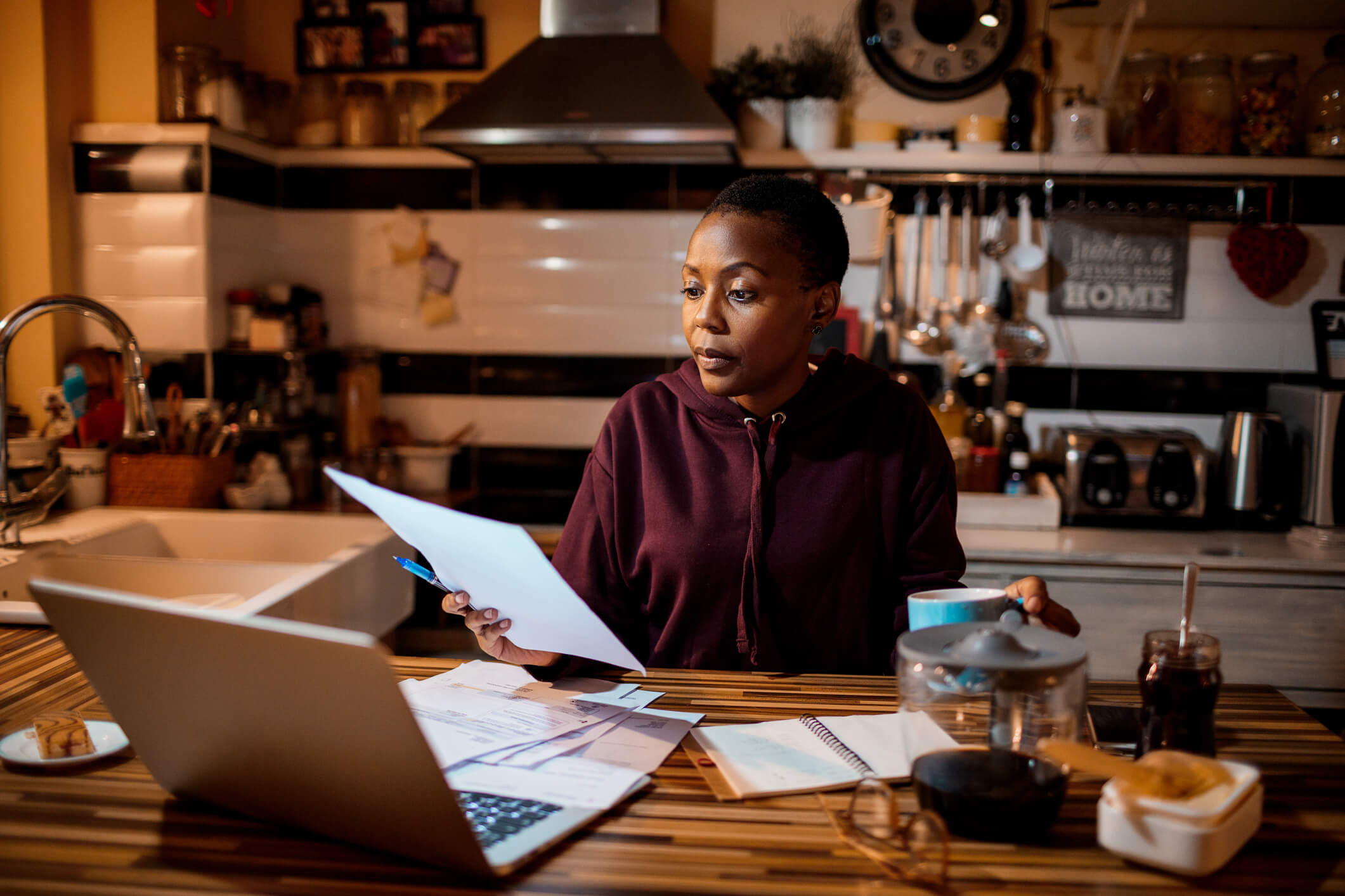 woman reviewing her finances at laptop in kitchen