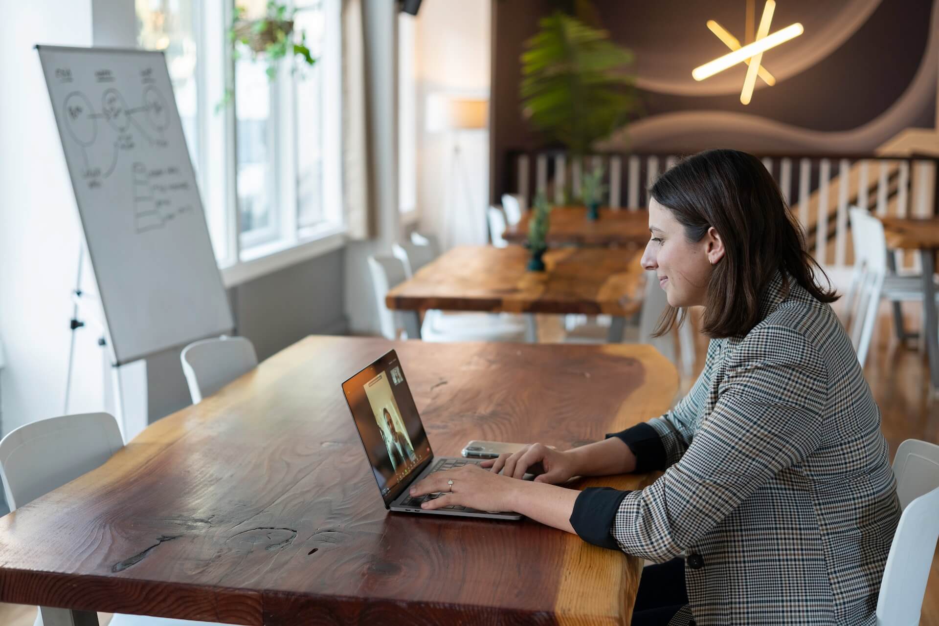 woman sitting at table in cafe on virtual meeting