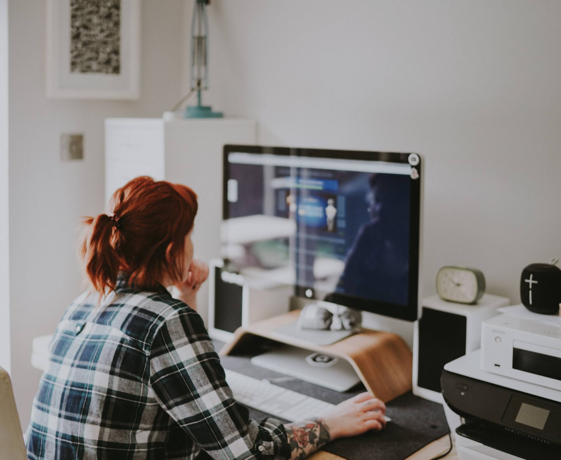 woman with red hair working at computer in white room