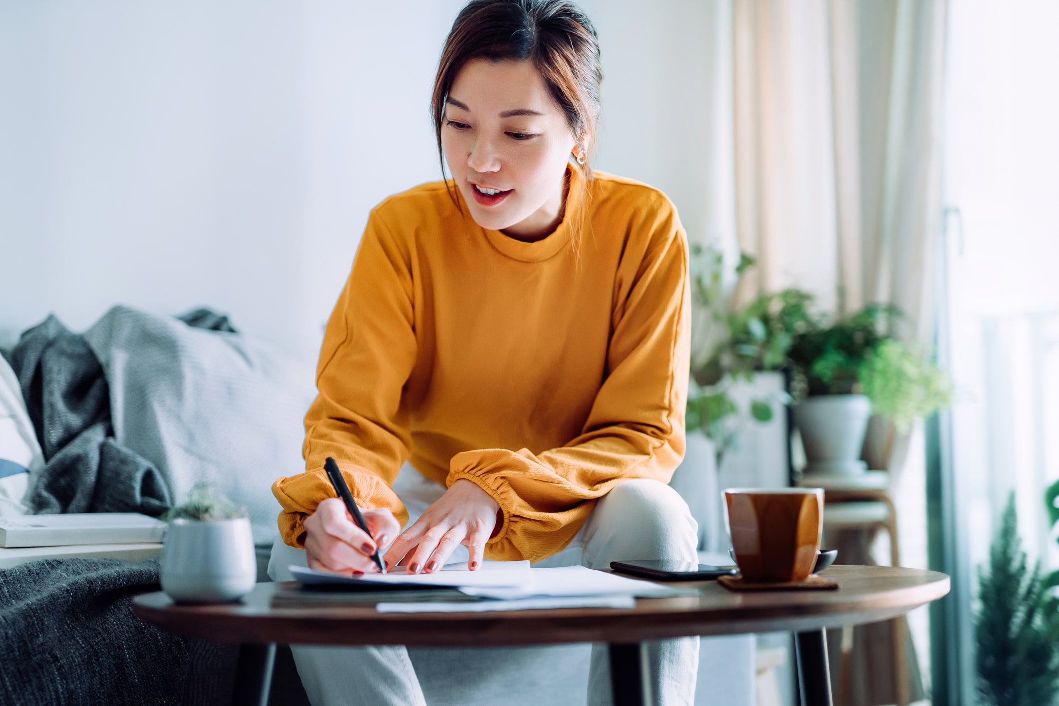 woman-holding-a- pen-and-writing-goals-in-the-living-room-types-of-goals