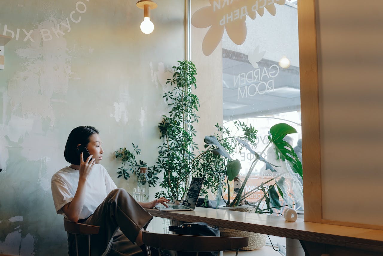 woman-in-white-shirt-sitting-on-chair-while-having-phone-call
