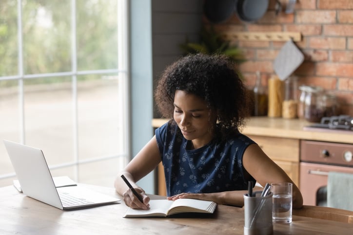 young-woman-writing-notes-in-paper-notebook-letter-of-interest