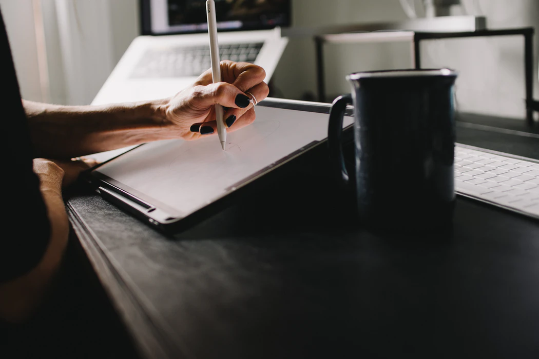 woman-writing-on-tablet-with-white-pen-and-coffee-cup-intellectual-curiosity