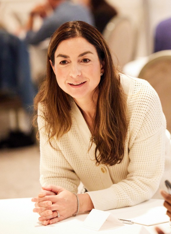 Gabriella Rosen Kellerman leaning over table listening