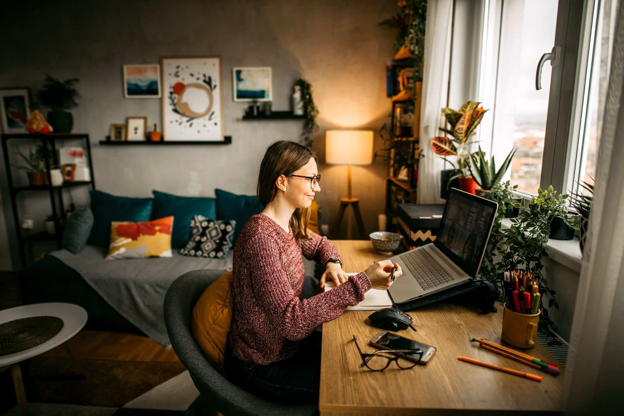 smiling woman sitting at desk working on laptop